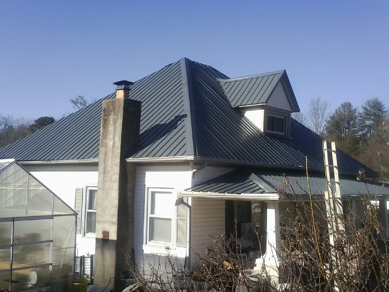 Dark blue standing seam metal roof on a white farmhouse with dormer — Slate & Tile Roof Repair by Roofing Brothers in Hiram