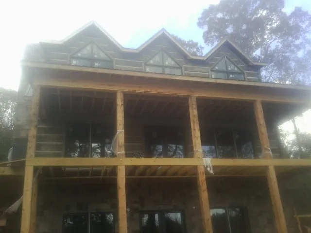 Dormers and porch framing on a large log home under construction — Roof Coating work by our crew in Hiram