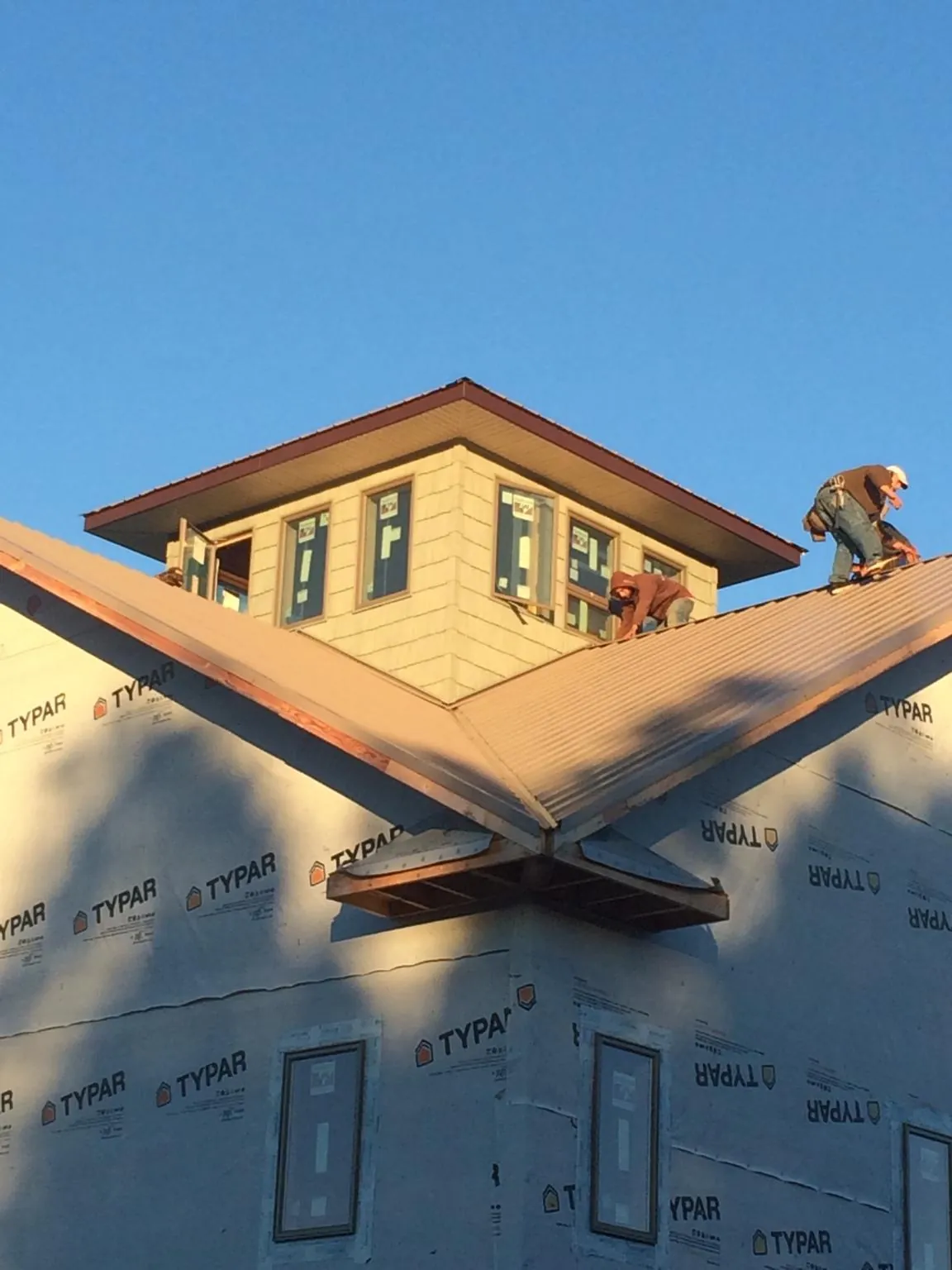 Roofers working around a rooftop cupola on a new metal roof at sunset — Roof Waterproofing in Hiram by Roofing Brothers